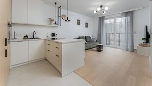 Een moderne keuken met witte kasten, een centraal eiland en een zithoek met een grijze bank.