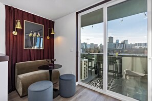 A modern living room with a sofa, ottomans, a small table, and a large sliding glass door to a balcony.