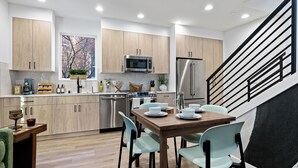 Eine moderne Küche mit Holzschränken, Edelstahlgeräten und einem Essbereich mit hellblauen Stühlen.