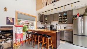 Una cocina moderna con una isla central, taburetes de bar y electrodomésticos de acero inoxidable.