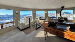 A spacious living room with large windows offering a panoramic view of a snowy landscape. - Working Ranch House with Astonishing Mountain & Valley Panoramic Views (Cañon City)
