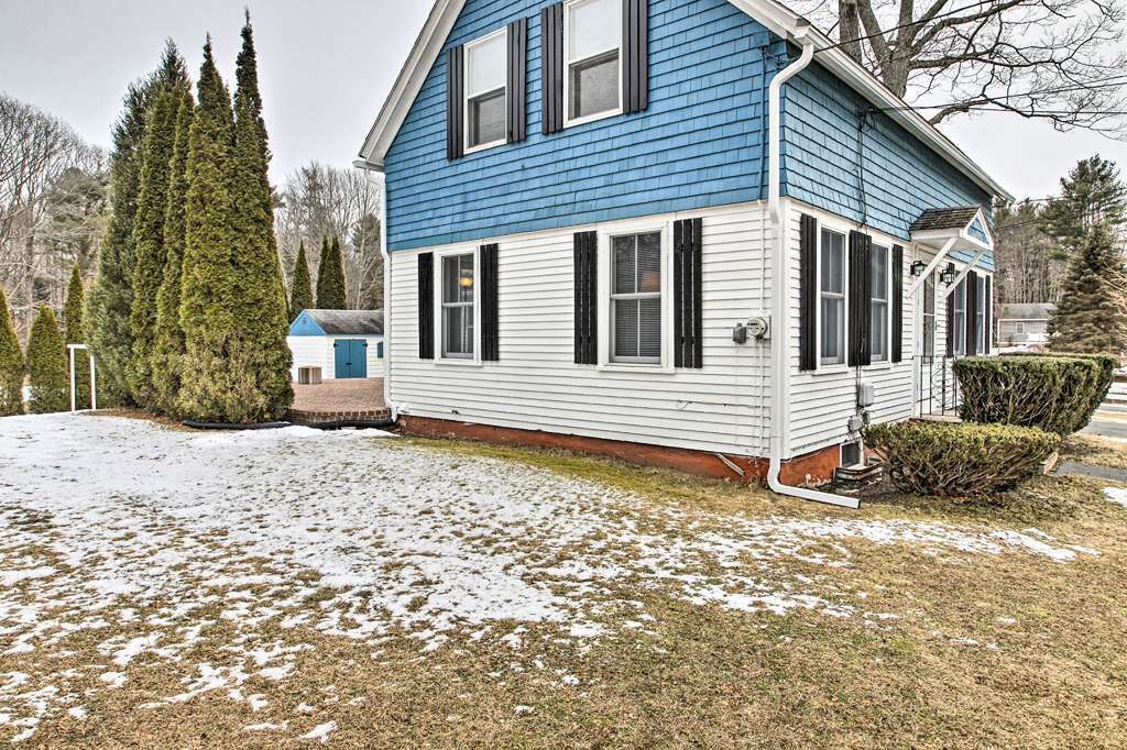 Una casa de dos pisos con fachada azul y blanca, un porche cubierto y un patio cubierto de nieve.
