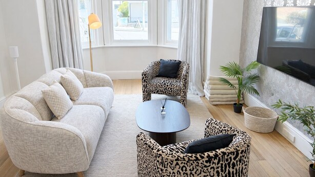 A modern living room with a sofa, two armchairs, a coffee table, and a TV. - Haven Hobart CBD (Hobart)