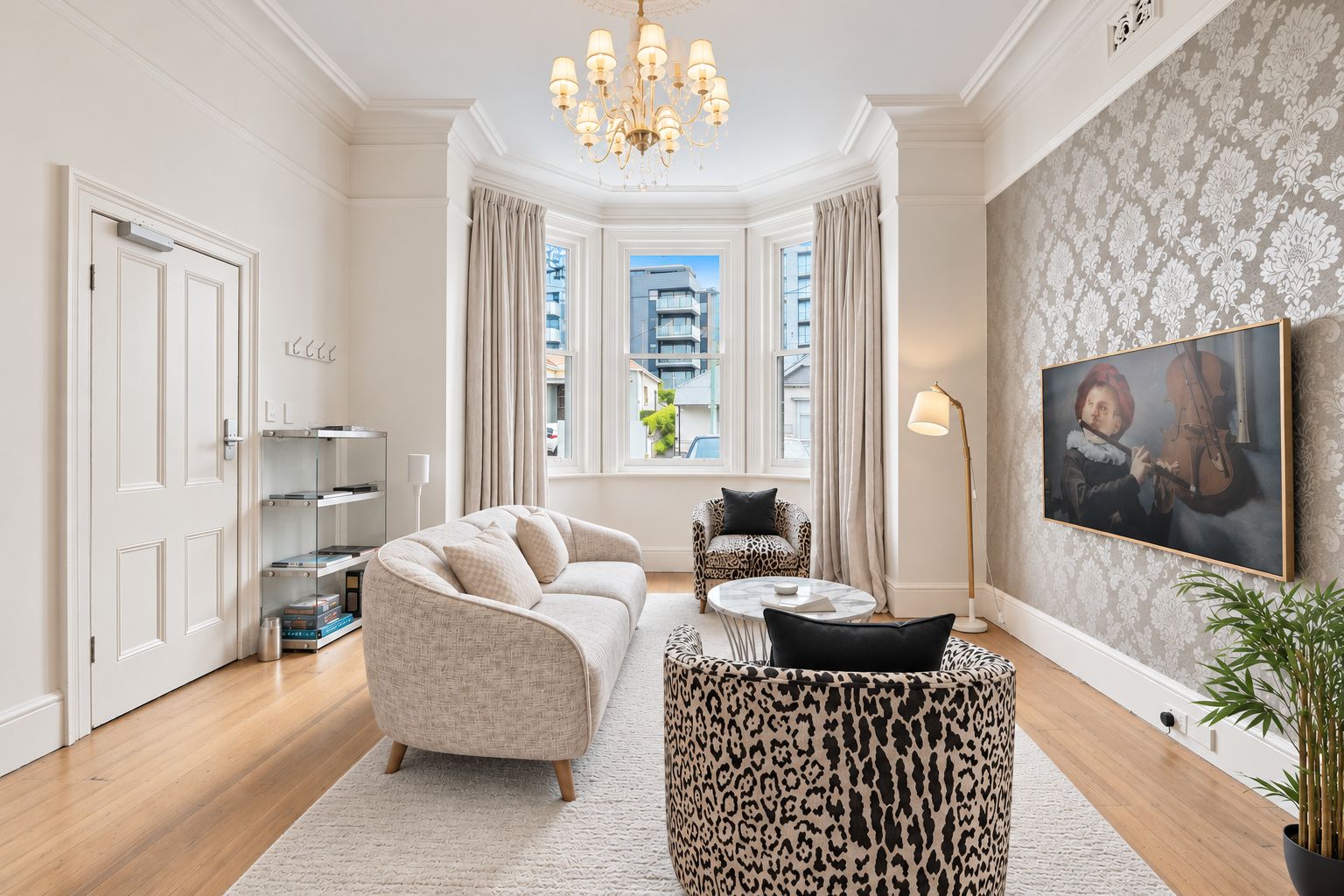 A modern living room with a sofa, a patterned coffee table, a leopard print rug, a painting, and a potted plant.
