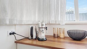 A kitchen counter with a coffee maker, kettle, and two glass containers. - Haven Hobart CBD (Hobart)