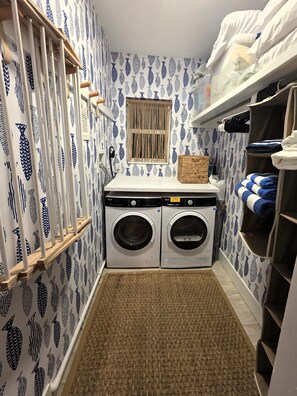 A laundry room with two front-loading washing machines, a drying rack, and a shelf with folded towels. - Oceanfront & Intracostal Private Villa Steps From the Beach (Hillsboro Beach)