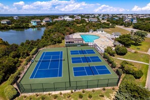Ein Luftbild eines Tennisplatzkomplexes mit mehreren Plätzen, einem Schwimmbad und umliegenden Wohnhäusern.