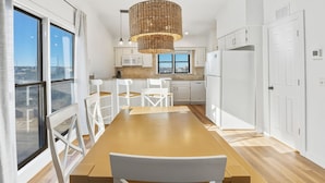 Een moderne keuken met witte kastjes, een houten eettafel en een groot raam.