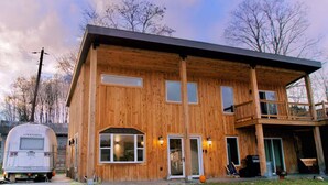 Een houten woonhuis met twee verdiepingen, een balkon, een garage en een groot raam.