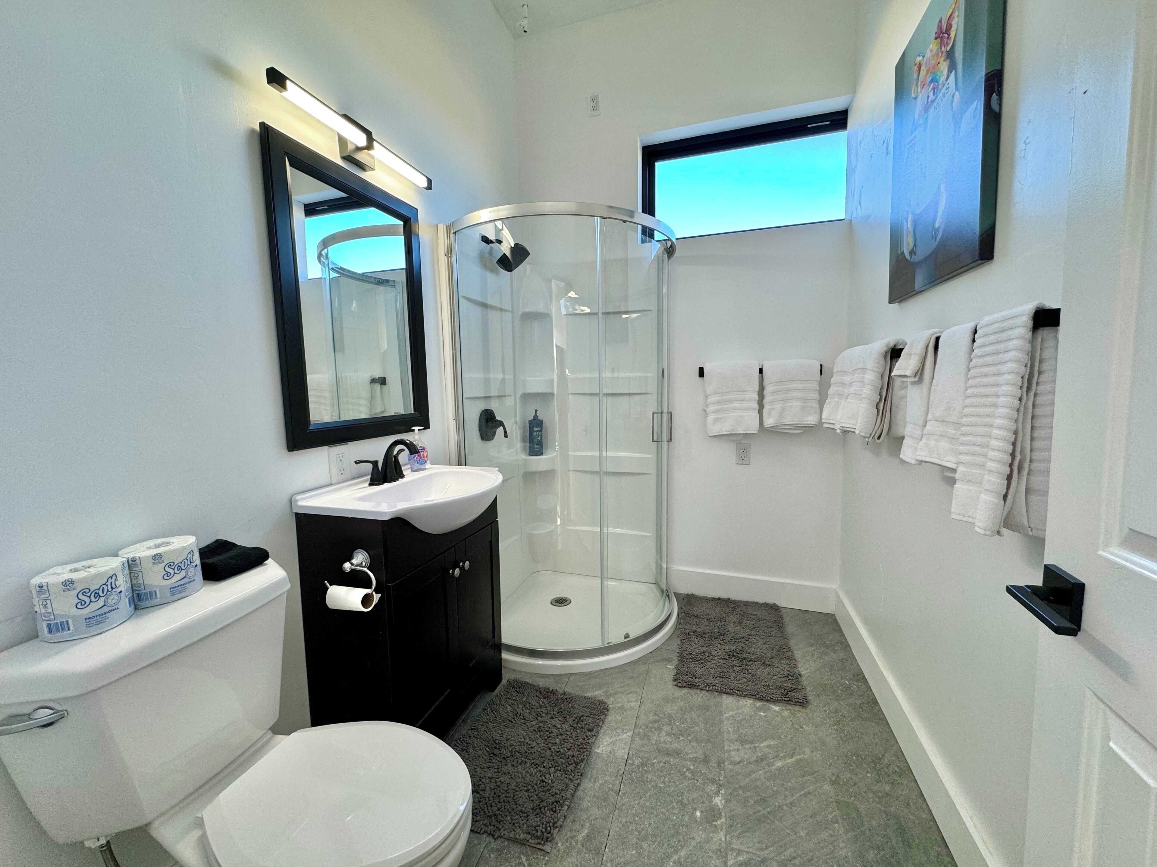 Un bagno moderno con servizi igienici, lavandino e box doccia in vetro.
