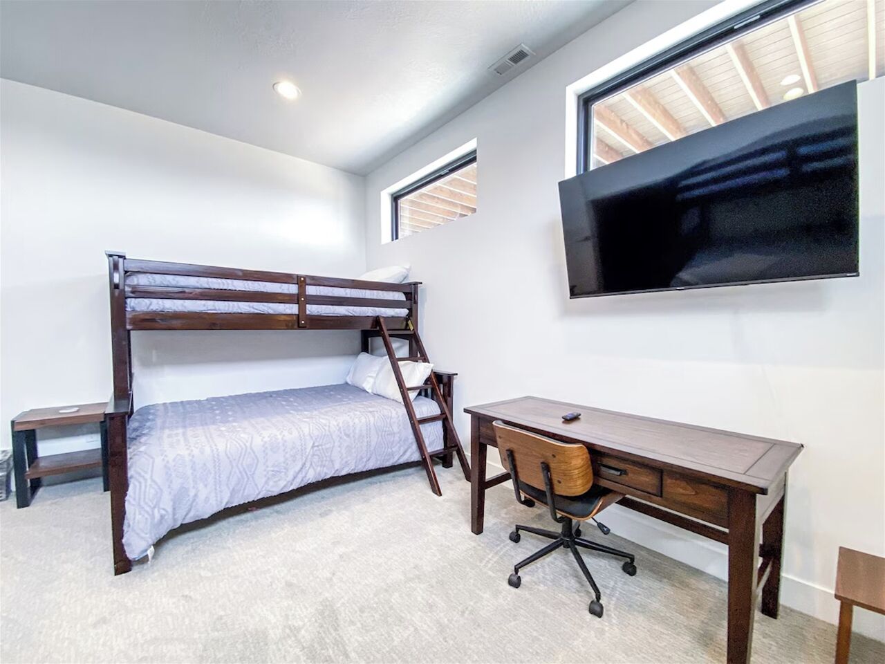 A bedroom with a bunk bed, a desk, and a chair.