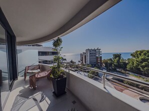 A balcony with wicker furniture and a potted plant, overlooking a coastal area with buildings and a clear sky. - Zins Luxury Room 02 in Durr s (Durrës)