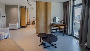 Een moderne hotelkamer met een bureau, stoel en een groot raam met gordijnen.