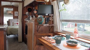 Et kompakt tekøkken med fjernsyn, kaffemaskine og ventilator.