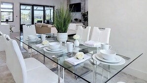Comedor moderno con una mesa de vidrio, sillas blancas y juego de comedor blanco.