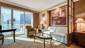 Une chambre d’hôtel moderne dotée d’une grande fenêtre, d’un canapé, d’un fauteuil, d’une table basse et d’une lampe.