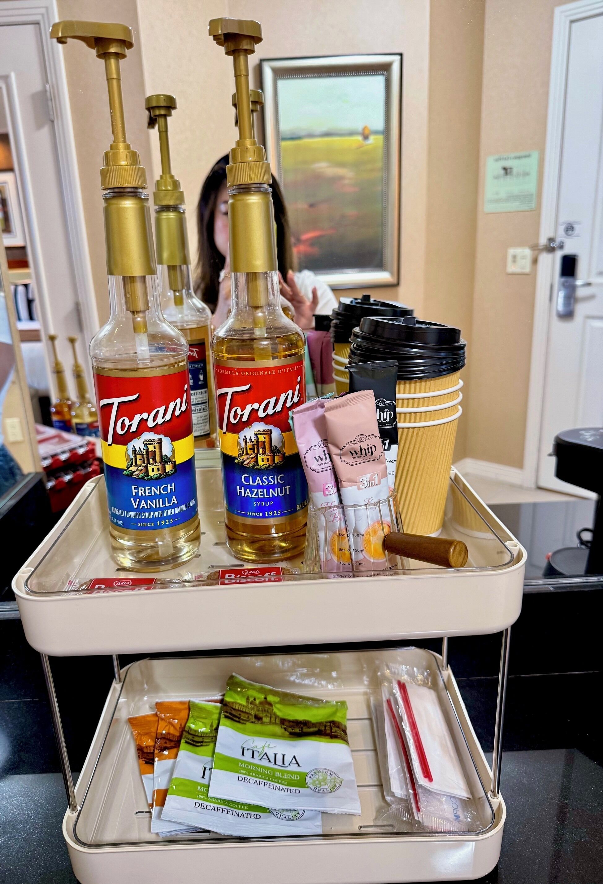 Camera d'albergo con un minibar, bottiglie di sciroppo Torani e un vassoio con tazze da caffè e bustine di tè.