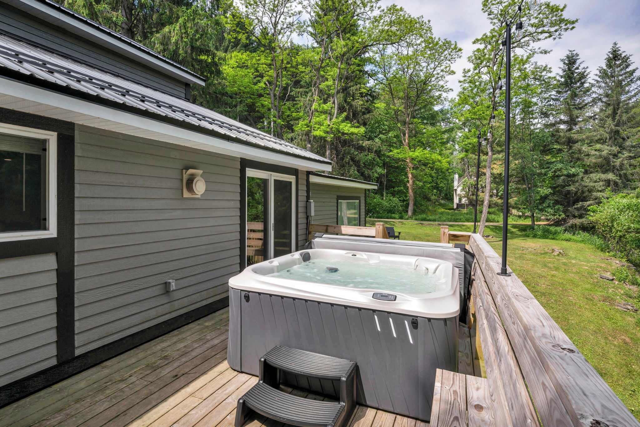 Private hot tub on a spacious deck surrounded by towering trees — soak beneath the open sky and let the peaceful forest scenery melt your stress away.