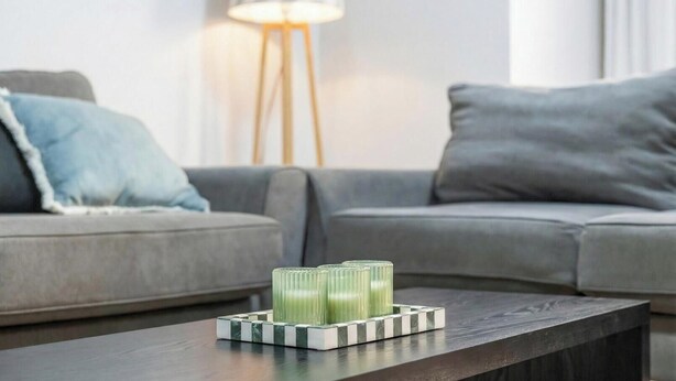 Una sala de estar moderna con una mesa de centro de madera oscura, sofás grises y una lámpara de pie.