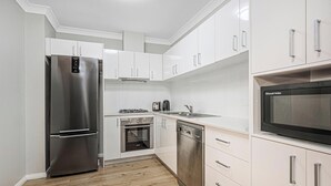 Una cocina moderna con armarios blancos, electrodomésticos de acero inoxidable y un microondas integrado.