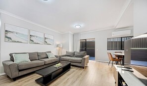 Una sala de estar moderna con un sofá, una mesa de centro y una obra de arte en la pared.
