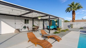 Eine moderne Außenpatio mit Lounge-Möbeln, einem Pool und einem überdachten Sitzbereich.