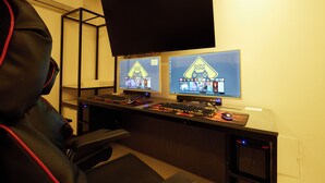 A gaming setup with two monitors displaying a game, a keyboard, and a mouse on a desk. - JM HOTEL (Suwon)