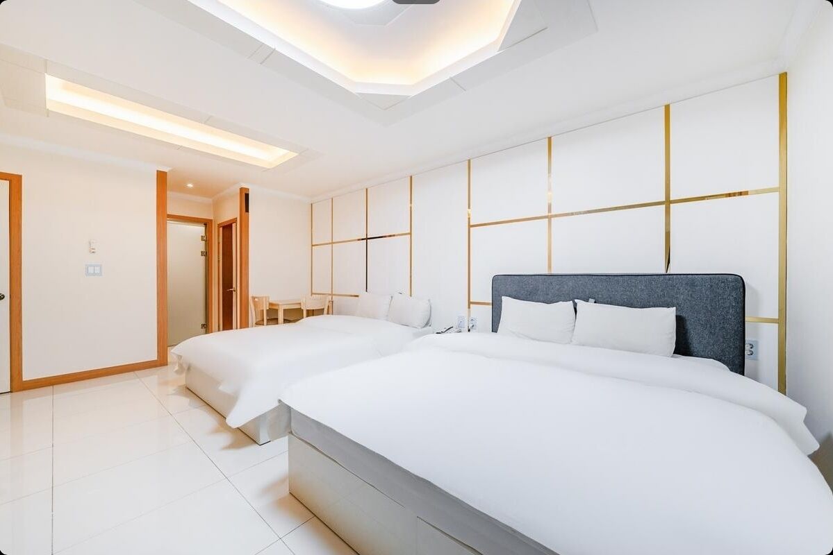 Quarto de hotel moderno com duas camas, um claraboia e design minimalista.