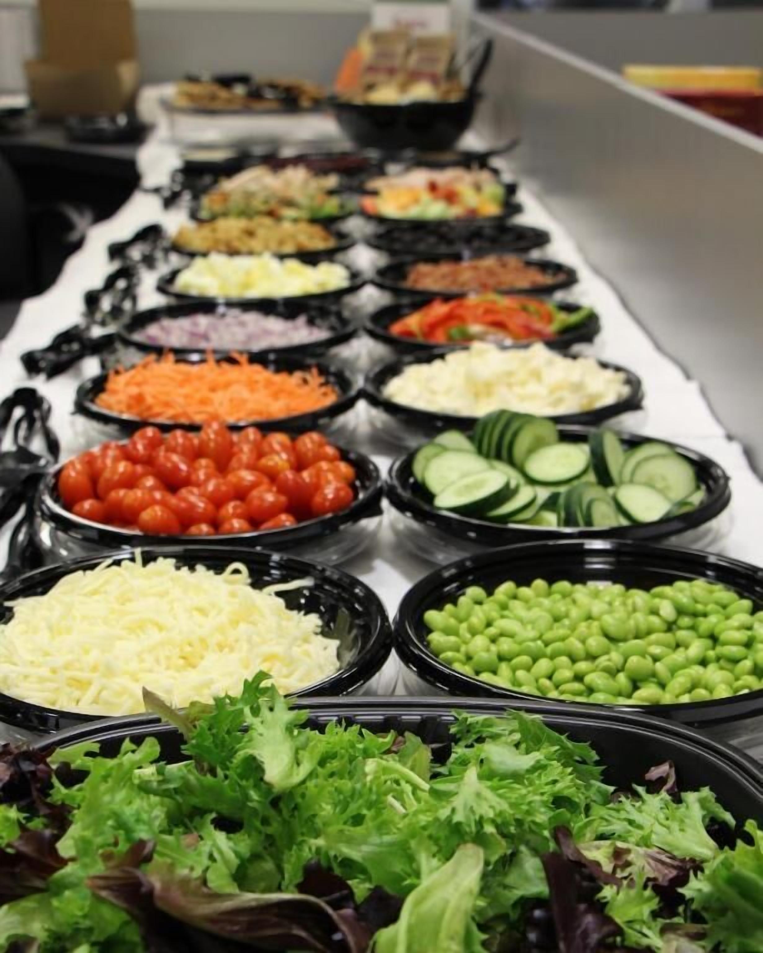 A buffet with various food items including salads, vegetables, and cheeses.