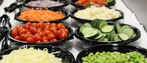 A buffet with various food items including salads, vegetables, and cheeses.
