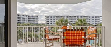 A balcony with a white table and chairs, a view of a residential building, and a tiled floor.