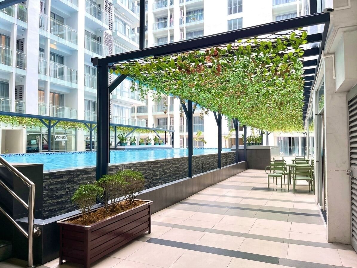 An indoor swimming pool area with a covered seating area and a planter with small trees.