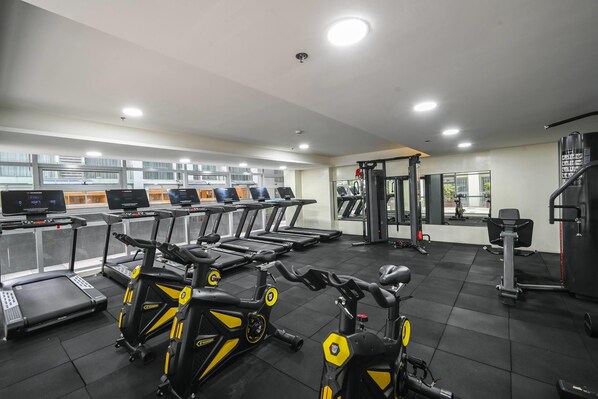 Un gimnasio con cintas de correr, bicicletas estáticas y máquinas de pesas.