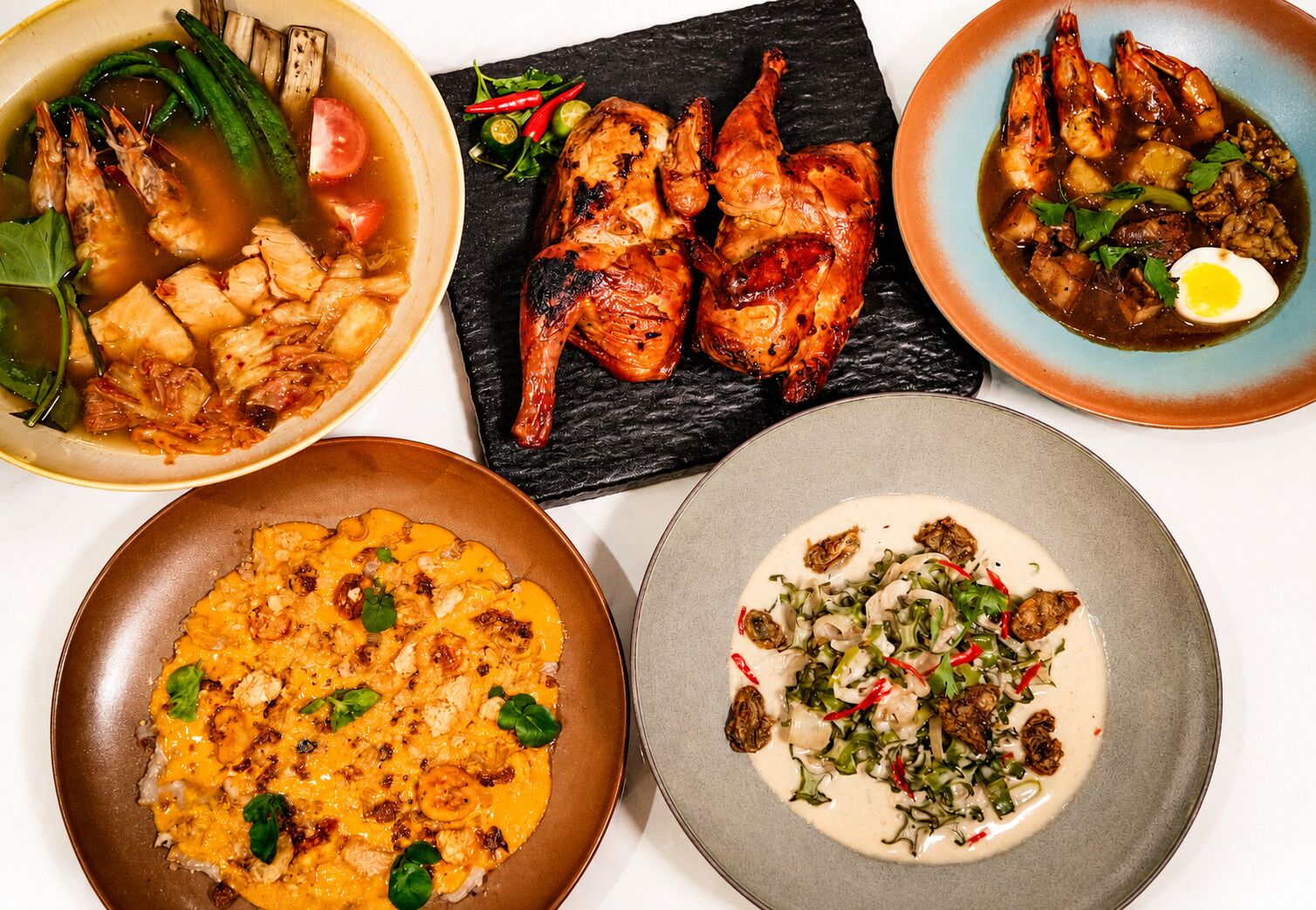 A variety of dishes including seafood, grilled chicken, and a creamy soup.