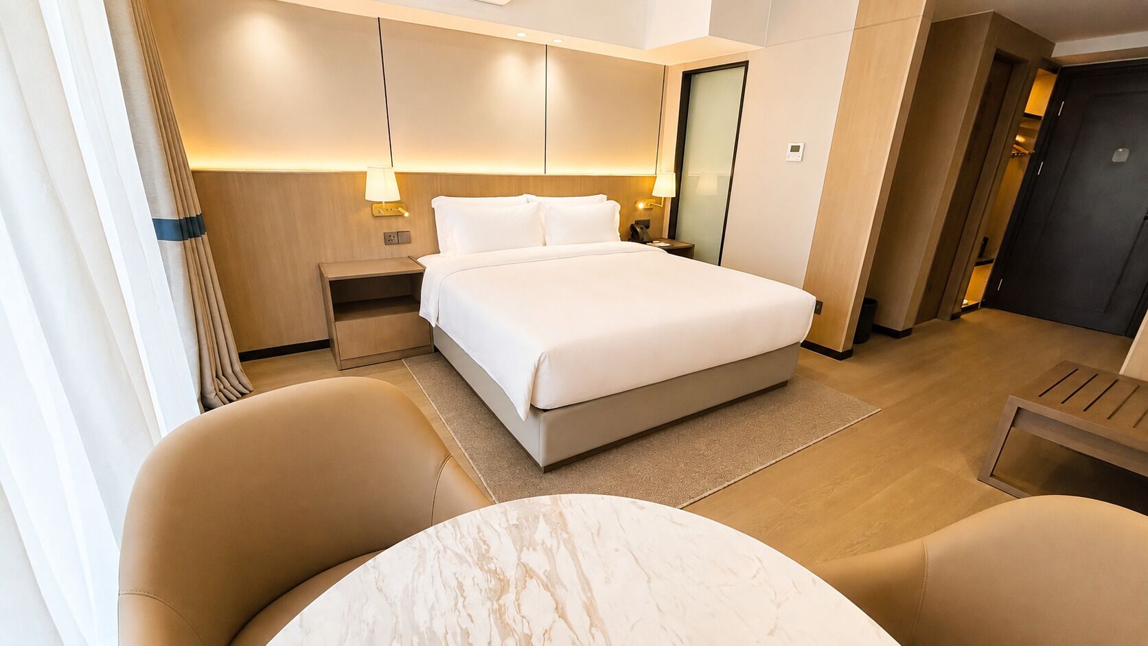 Une chambre d’hôtel avec un lit, des tables de chevet, un bureau et une chaise.