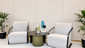A modern seating area with two chairs and a round table, featuring minimalist design and potted plants. - Wyndham Garden Manila Bay (Parañaque)