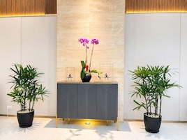 Un comptoir d'accueil avec une nappe grise, deux plantes en pot et un vase contenant des orchidées.