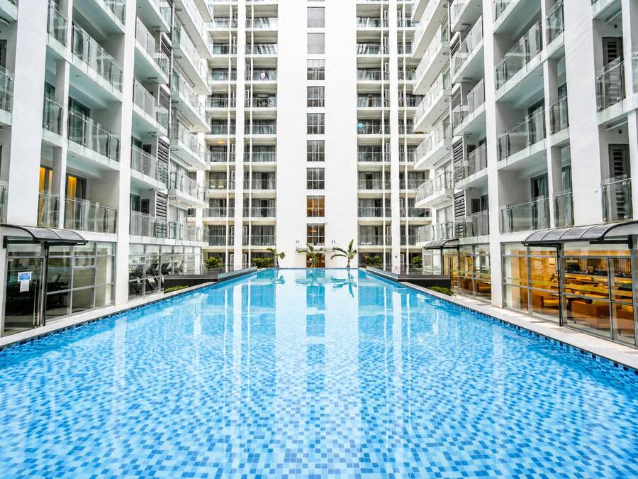 Un interior de hotel moderno con una piscina central, varios balcones y un diseño limpio y contemporáneo.
