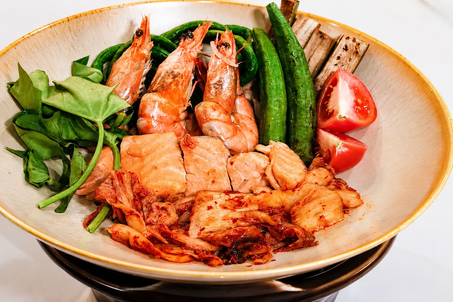 A plate with cooked shrimp, vegetables, and a slice of tomato.