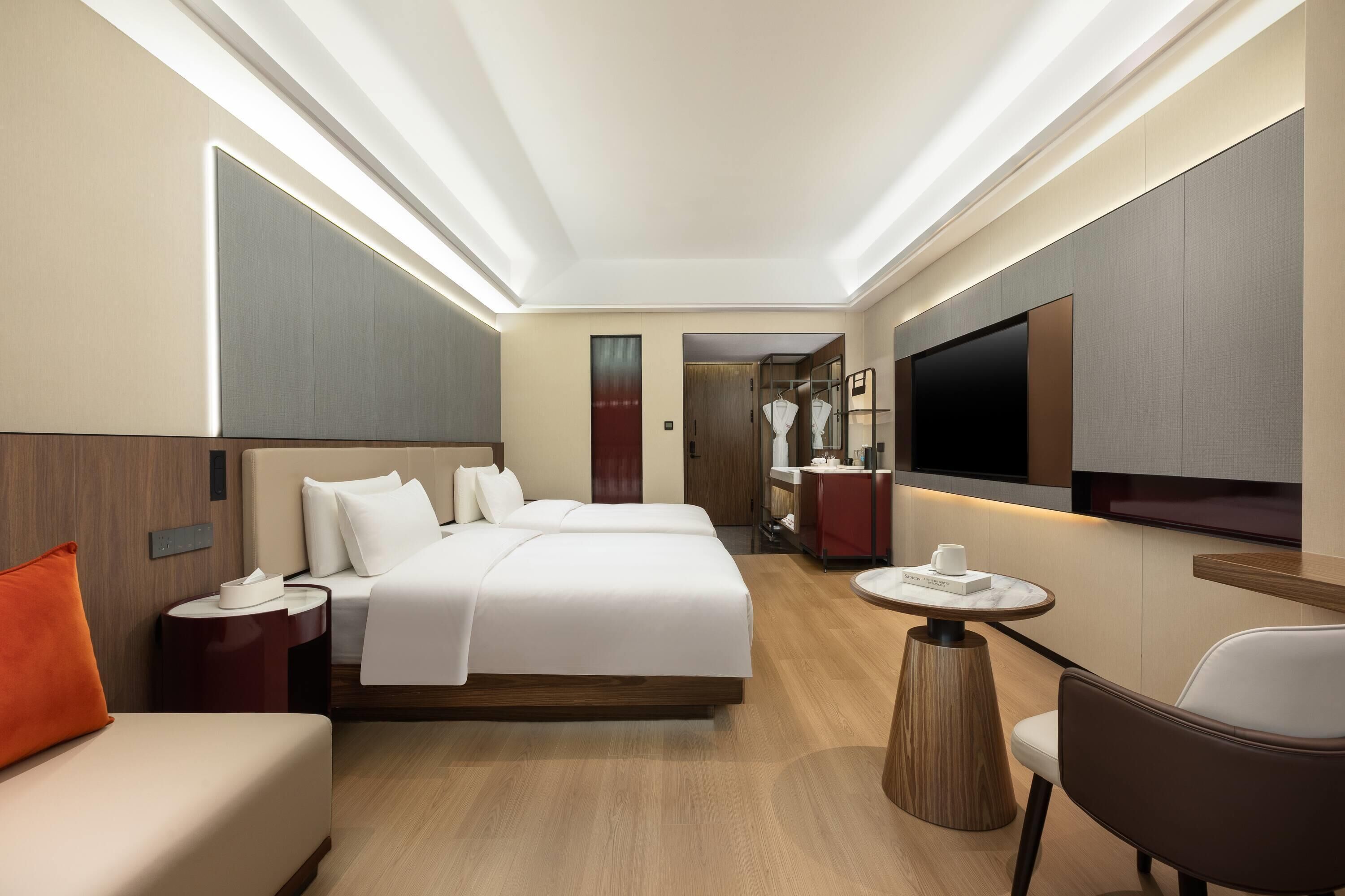 A hotel room with a large bed, a TV, a desk, and a chair.