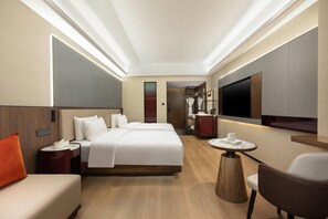 Une chambre d’hôtel avec un grand lit, une télévision, un bureau et une chaise.