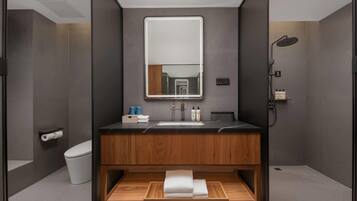 A modern bathroom with a wooden vanity, a large mirror, a shower, and a toilet.