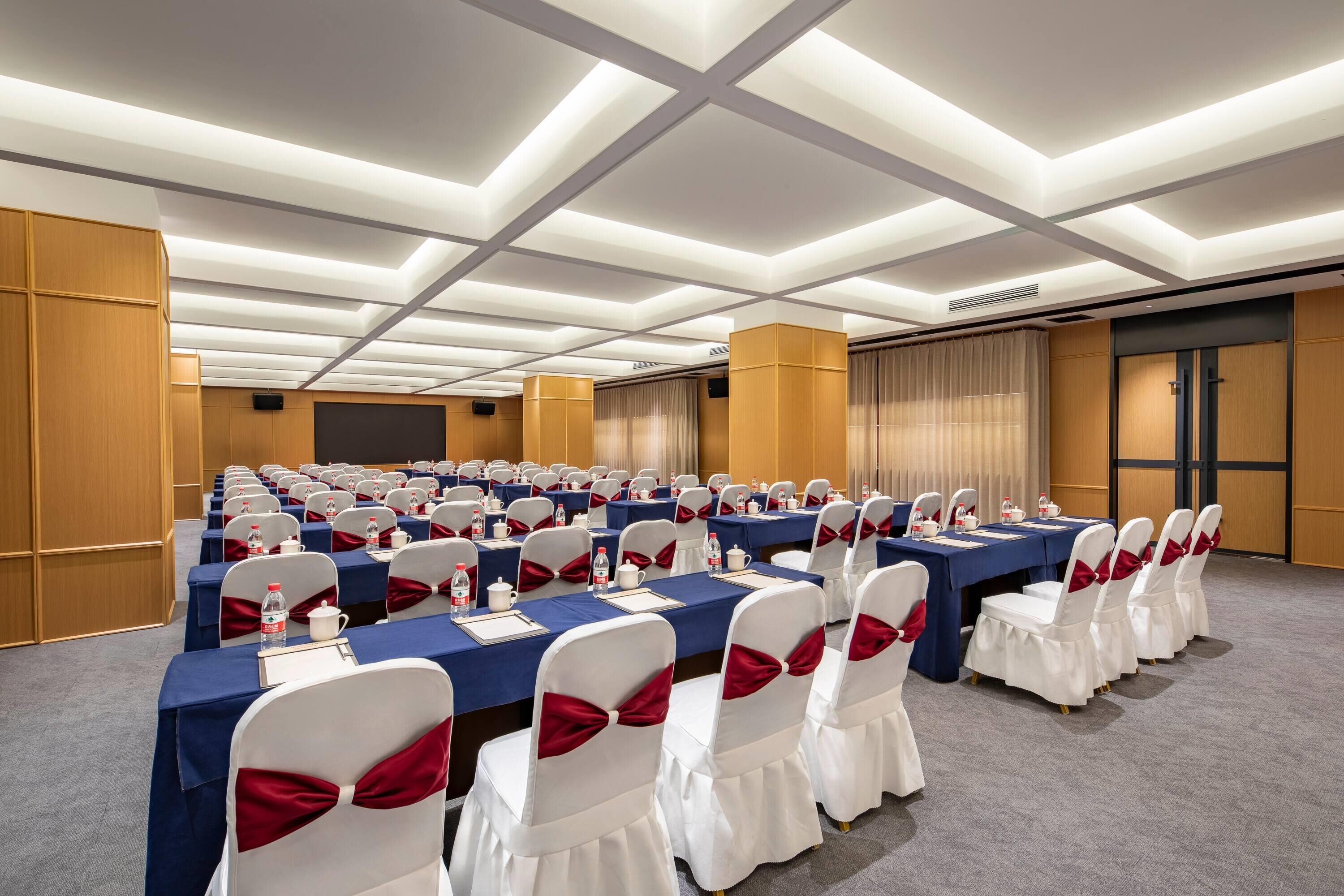 A conference room with rows of tables, chairs, and a podium.
