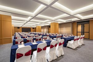 Un salón de conferencias con mesas, sillas y un atril.