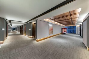 A modern hotel corridor with a patterned carpet, recessed lighting, and a wooden ceiling. - Hawthorn By Wyndham Yueyang Railway East Station (Yueyang)