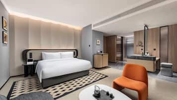 Una habitación de hotel moderna con cama, escritorio, silla, baño y zona de comedor.
