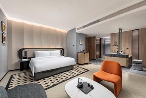 Moderni hotellihuone, jossa on sänky, työpöytä, tuoli, kylpyhuone ja ruokailutila.