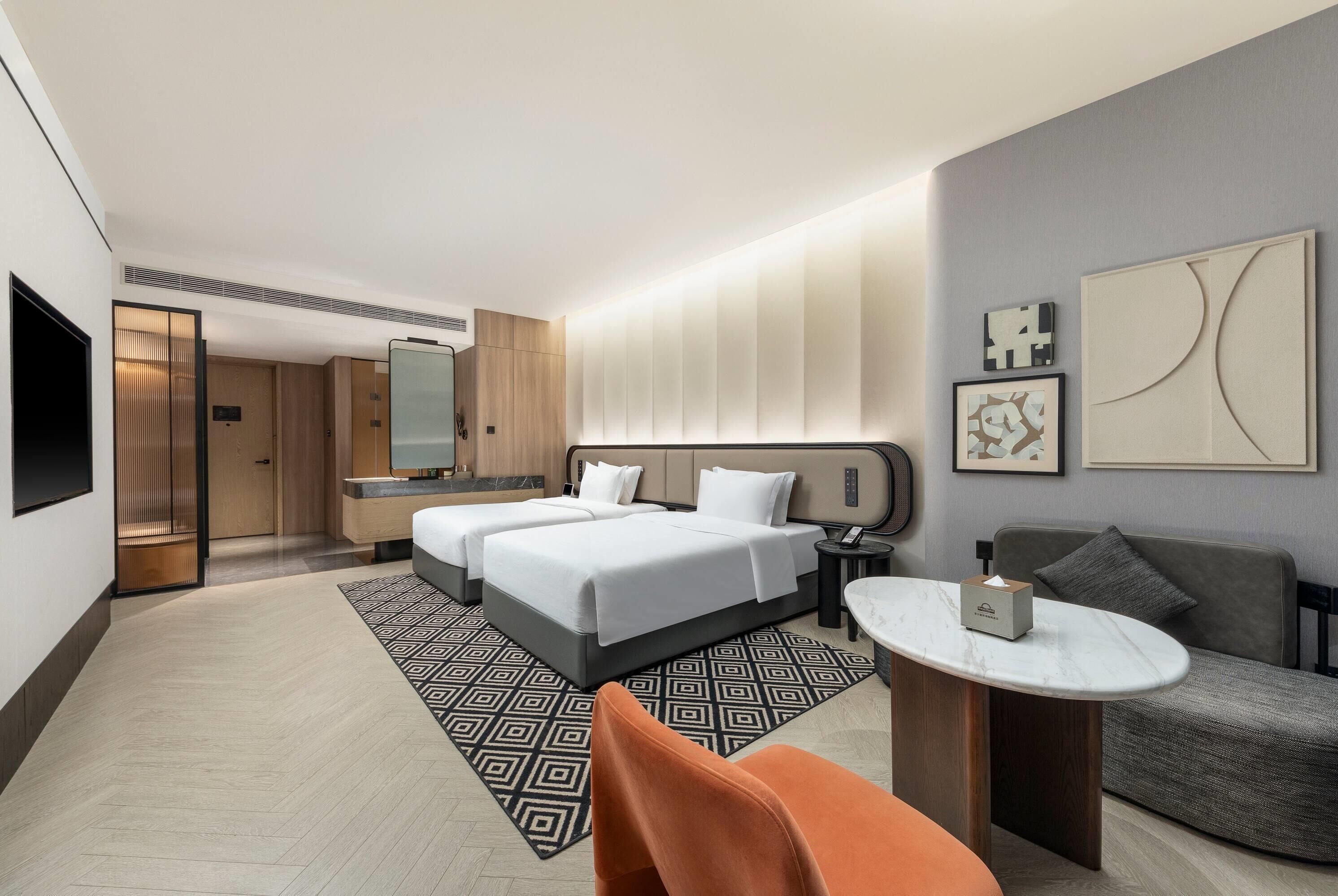 A hotel room with two beds, a sitting area with a table, and a sofa.
