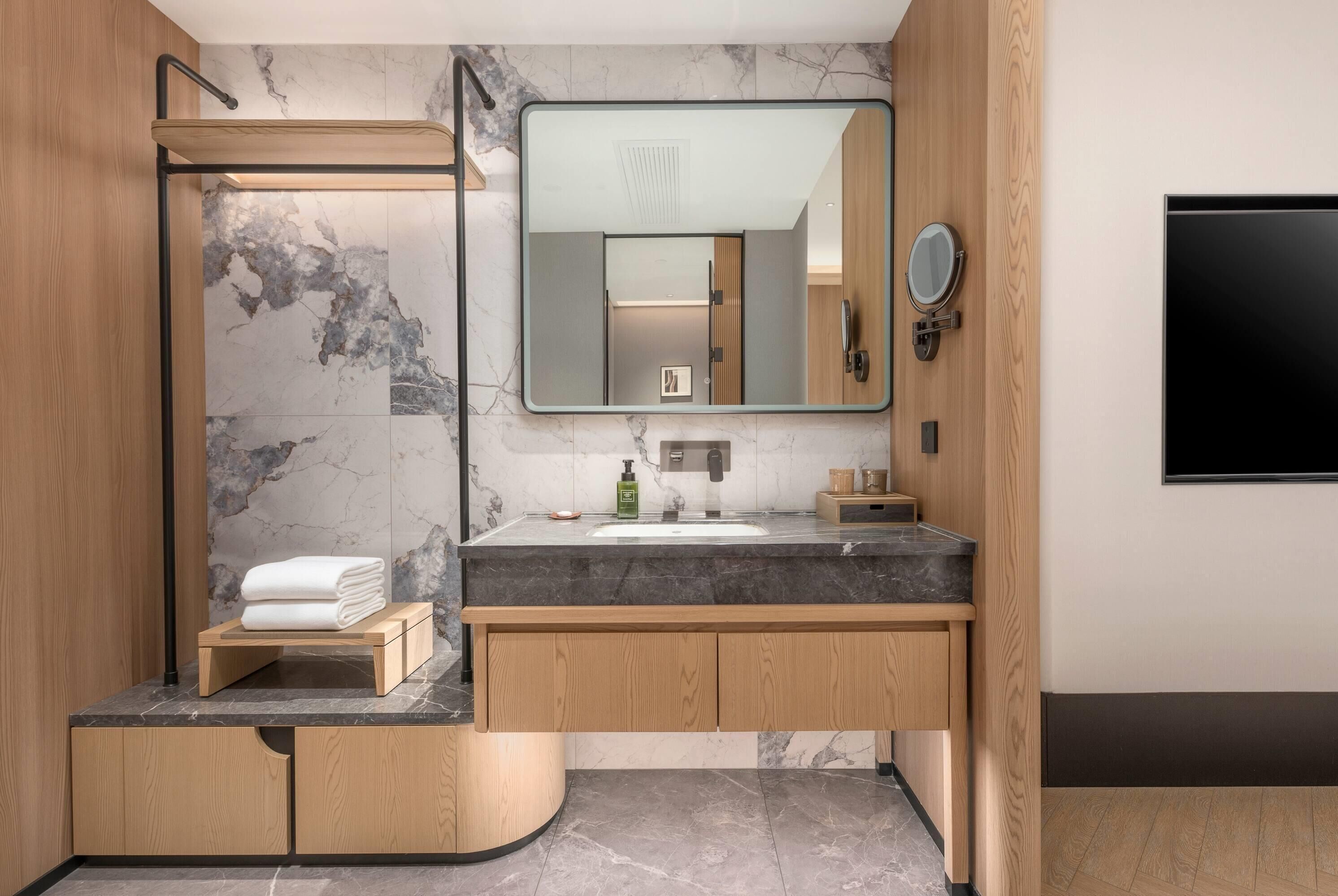 Une salle de bain moderne avec un meuble-lavabo en marbre, un grand miroir et une douche intégrée.
