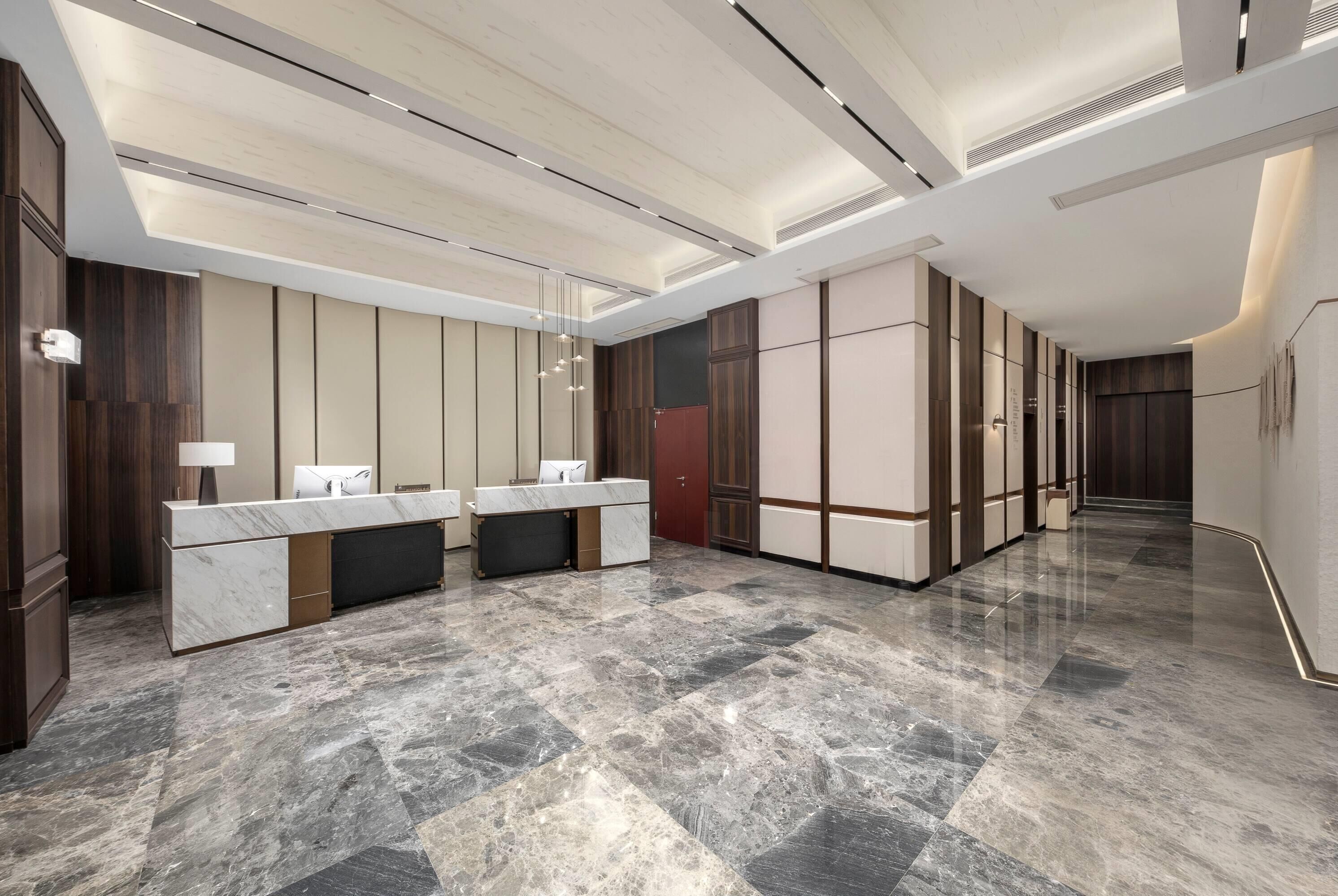 Un moderno vestíbulo de hotel con una recepción de mármol, paneles de madera oscura y un piso pulido.